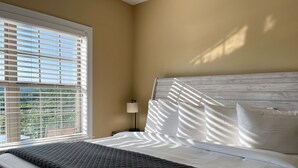 A bedroom with a bed, a nightstand, a lamp, and a window with blinds. - Eagle's View - No Stairs - Minutes to SDC (Branson)