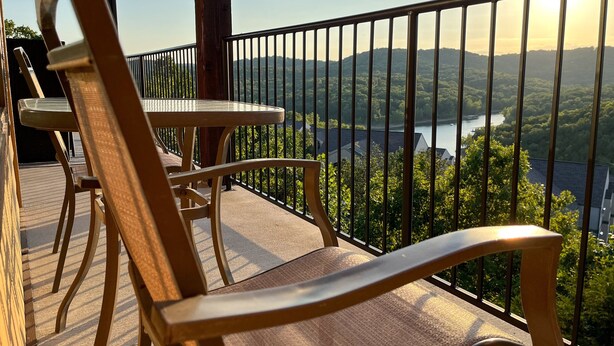 A balcony with wooden chairs and a table, overlooking a scenic view of a lake and mountains. - Eagle's View - No Stairs - Minutes to SDC (Branson)