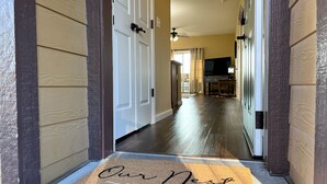 A hallway with a doormat reading "Our Nest" leading to a dining area with a table and chairs. - Eagle's View - No Stairs - Minutes to SDC (Branson)