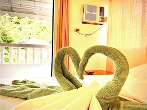 Relax in a serene setting with a view of lush greenery from the window, featuring a cozy bed with a wooden headboard.