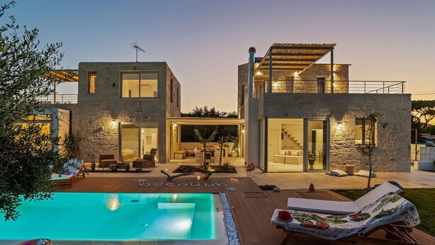 A modern two-story house with a swimming pool, outdoor seating, and a stone facade. - Villa Annassa Almyrida (CHANIA)