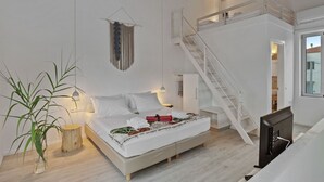 A bedroom with a bed, a staircase, a TV, and a plant. - Villa Annassa Almyrida (CHANIA)