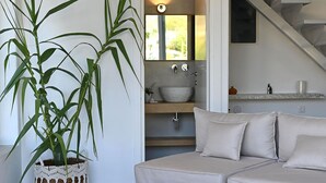 A modern living room with a grey sofa, a large potted plant, and wicker ottomans. - Villa Annassa Almyrida (CHANIA)