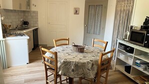 Cocina compacta con mesa, sillas, microondas y cafetera.