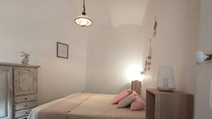 Un dormitorio con cama, mesita de noche, lámpara y adornos en la pared.