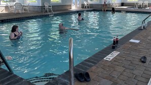Une piscine intérieure à l’eau claire, dotée d’un sol carrelé et d’une échelle métallique.
