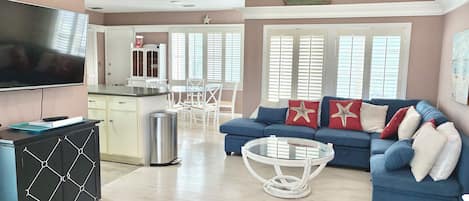 A living room with a blue sofa, white coffee table, and a TV on a cabinet.