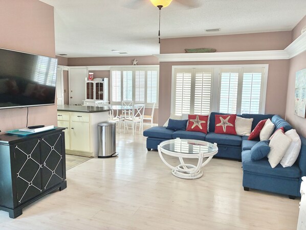 A living room with a blue sofa, white coffee table, and a TV on a cabinet.