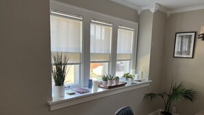 Ein Zimmer mit einem großen Fenster, einem Sessel und einem Blumentopf.