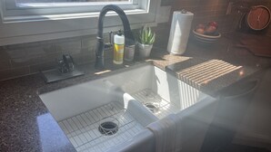 Eine Küche mit einer Granitabdeckung, einer Edelstahlspüle, einem Fenster über der Spüle und einem Handtuch am Wasserhahn.
