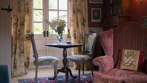A room with a dining table, two chairs, a floral curtain, a window with a view, and a red upholstered armchair. - Beau Repaire -  Castle Howard, Coneysthorpe , Yorkshire (York)