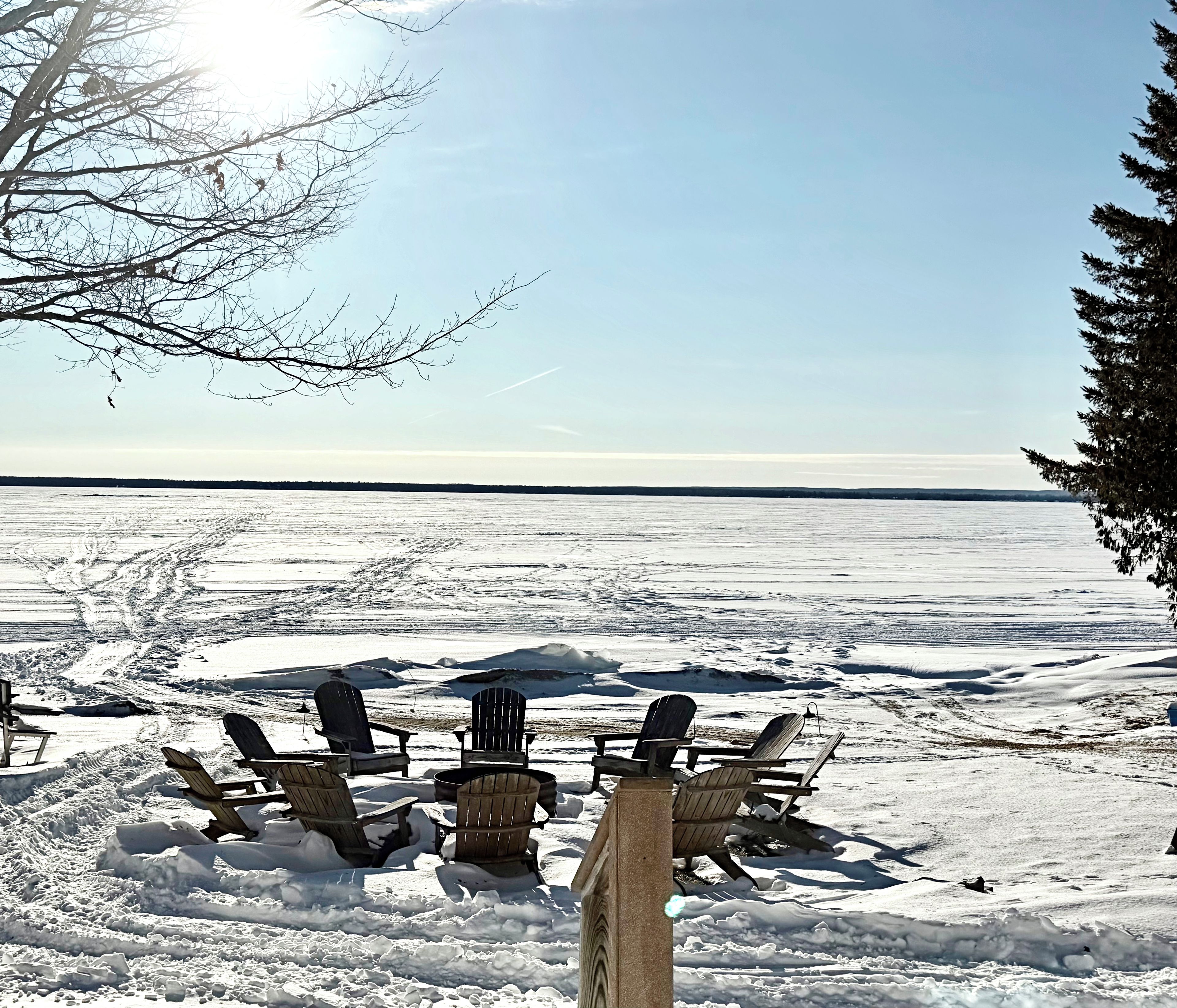 A snowy outdoor area with several Adirondack chairs arranged for seating.