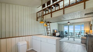 Un intérieur à thème nautique, avec un pont en bois, des meubles blancs et une vue sur la mer.