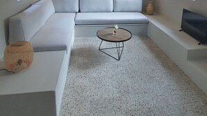 Een moderne woonkamer met een modulaire bank, een ronde salontafel en een televisie op een inbouwplank.