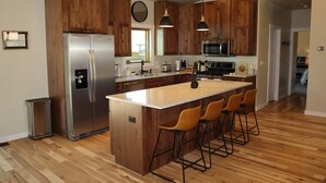 Una cocina moderna con armarios de madera, electrodomésticos de acero inoxidable y una isla central con taburetes de bar.