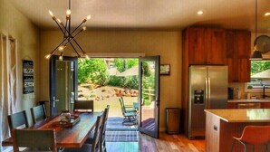 Una cocina moderna con una isla integrada, electrodomésticos de acero inoxidable y un comedor con mesa y sillas de madera.