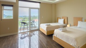 Ein Hotelzimmer mit zwei Betten, einem Balkon mit einem Stuhl und Blick auf die Landschaft.