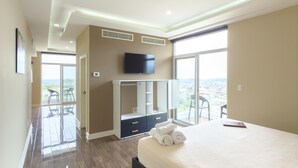Ein modernes Hotelzimmer mit einem großen Bett, einem Kleiderschrank, einem Flachbildfernseher und einem Balkon mit Sitzgelegenheiten.