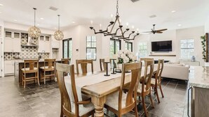 Una cocina amplia con zona de comedor, ventanas grandes y una lámpara de araña moderna.