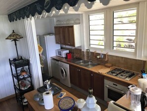 A compact kitchen with a washing machine, microwave, sink, and stove.