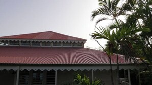 A building with a red roof and a white base, featuring a series of windows and a porch area.