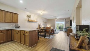 Une cuisine moderne avec des meubles en bois, un îlot central et un coin repas comprenant une table et des chaises.