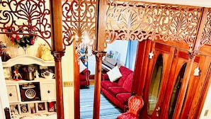 A staircase with a wooden railing leading to a living room with a red sofa and a wooden cabinet. - Charming Country Victorian Farm House (Barton)
