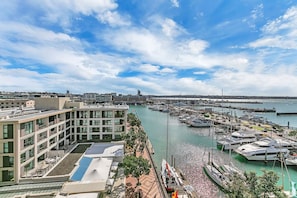 A marina with boats, a modern building with balconies, and a clear sky. - The Penthouse - Sebel (Auckland)