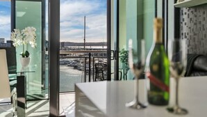 Ein modernes Zimmer mit Blick auf eine Marina und eine Brücke, ein Glastisch mit Flasche und Glas sowie eine Topforchidee.