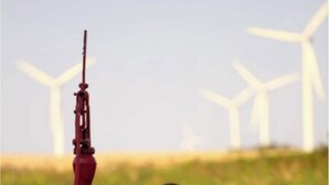 Il s’agit d’une maquette d’une tour rouge surmontée d’un long mât, reposant sur une petite base en béton, et agrémentée d’un pot de fleurs aux couleurs vives. On aperçoit des éoliennes à l’arrière-plan.