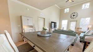 Amplia sala de estar con una gran mesa de comedor de madera, un sofá y una televisión.