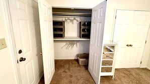 Ein Zimmer mit Schrank, Kleiderstange und kleiner Regalwand.