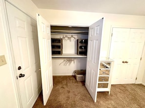 A room with a closet, a hanging rack, and a small shelf unit. - Cozy Downtown Destination (Raleigh)