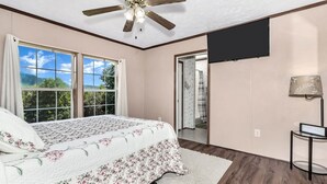A bedroom with a bed, a ceiling fan, a TV, and a view of the outdoors. - Private, cozy home - Handicapped Accessible no by- with great views  (Fletcher)