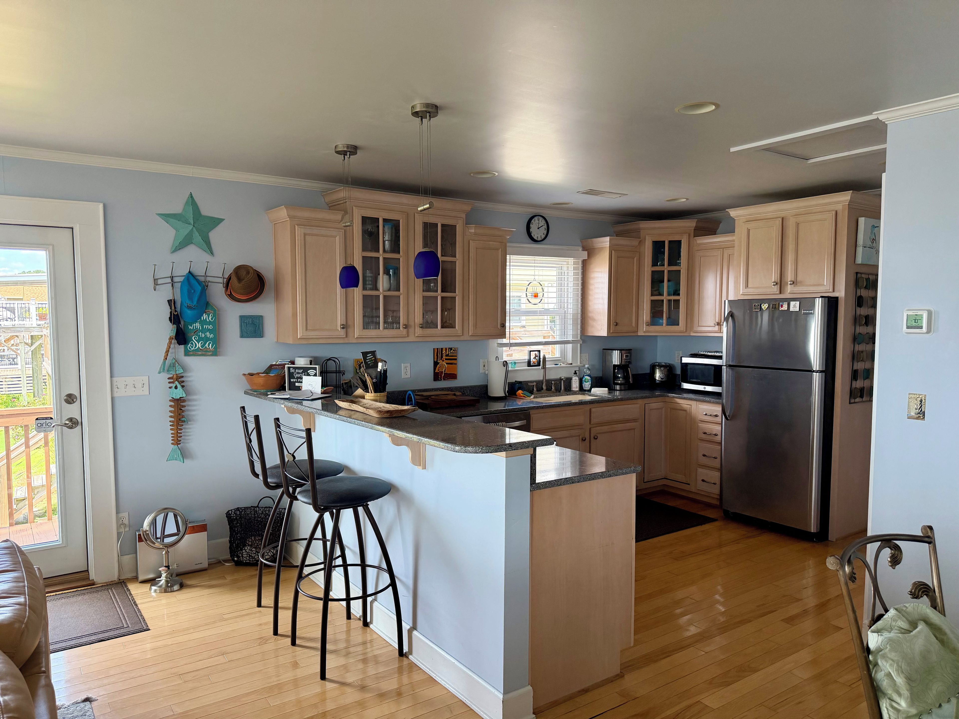 Una cocina con armarios de madera, un refrigerador de acero inoxidable y una ventana con persianas.