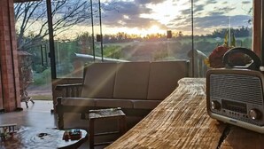 Un salon moderne avec une grande fenêtre, une table en bois, un canapé et une radio ancienne.