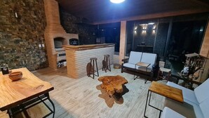 Un intérieur chaleureux avec une cheminée en briques, une table à manger en bois, un pouf en cuir et un canapé blanc.