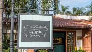 Une enseigne pour le restaurant-pizzeria Da Fonte, avec un toit recouvert de tuiles et des plantes en pot devant l’entrée.