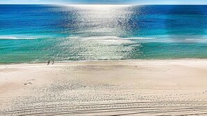 Una playa con vista despejada al océano y algunas personas caminando sobre la arena.