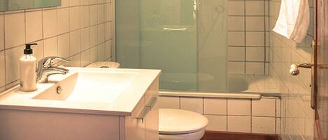 A bathroom with a sink, toilet, and glass-enclosed shower.