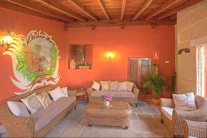 A cozy living room with wicker furniture, a wall mural, and a potted plant. - Finca Los Viñedos (Tacoronte)