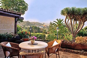 An outdoor patio with wicker furniture, a round table, and a vase of flowers. - Finca Los Viñedos (Tacoronte)