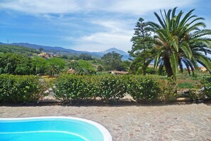 A swimming pool with a stone patio, surrounded by lush greenery and palm trees, with a mountainous backdrop. - Finca Los Viñedos (Tacoronte)