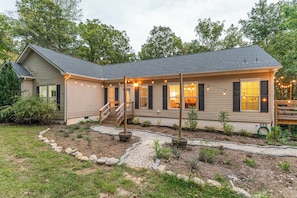 A two-story house with a covered porch, a stone pathway, and a small garden. - 6BR • Arcade & Pool Table • Hot Tub • Wine Country (Faber)