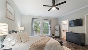 Ein Schlafzimmer mit einem Bett, Nachttischen, einem Schminktisch, einem Fernseher und einem Deckenventilator.