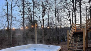 Ein Whirlpool in bewaldeter Landschaft mit einer Holztreppe und Lichterketten.