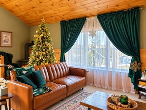 A cozy living room with a leather sofa, a Christmas tree, and a fireplace.
