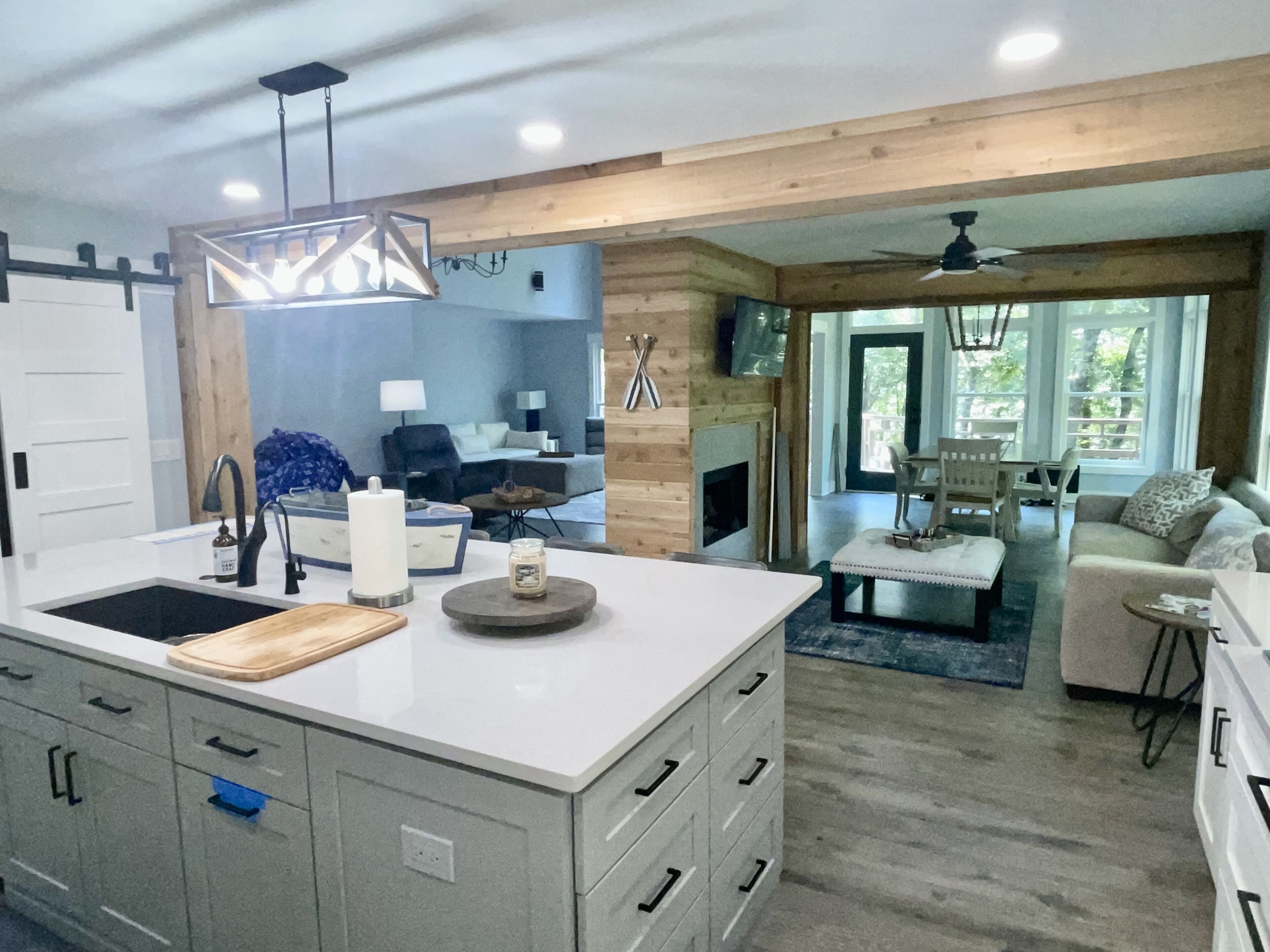 A modern kitchen with a central island, grey cabinetry, and a dining area with a sofa and table.