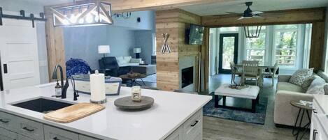 A modern kitchen with a central island, grey cabinetry, and a dining area with a sofa and table.