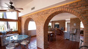 A dining area with brick arches, a glass table, and metal chairs. - Superstition Mountains Apache Junction - sleeps 16 (Apache Junction)